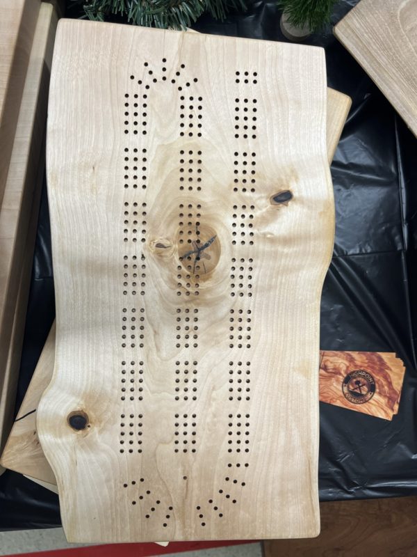 live edge maple slab with cribbage holes drilled in it